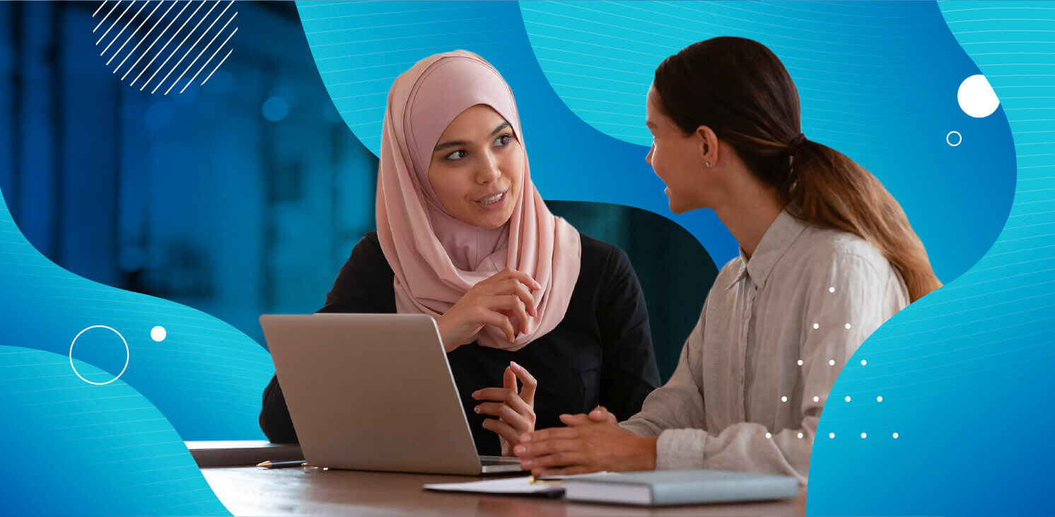 Two women talking over a computer with blue graphics surrounding them