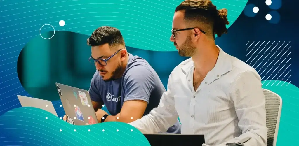 Two coworkers writing a follow up email on a laptop together